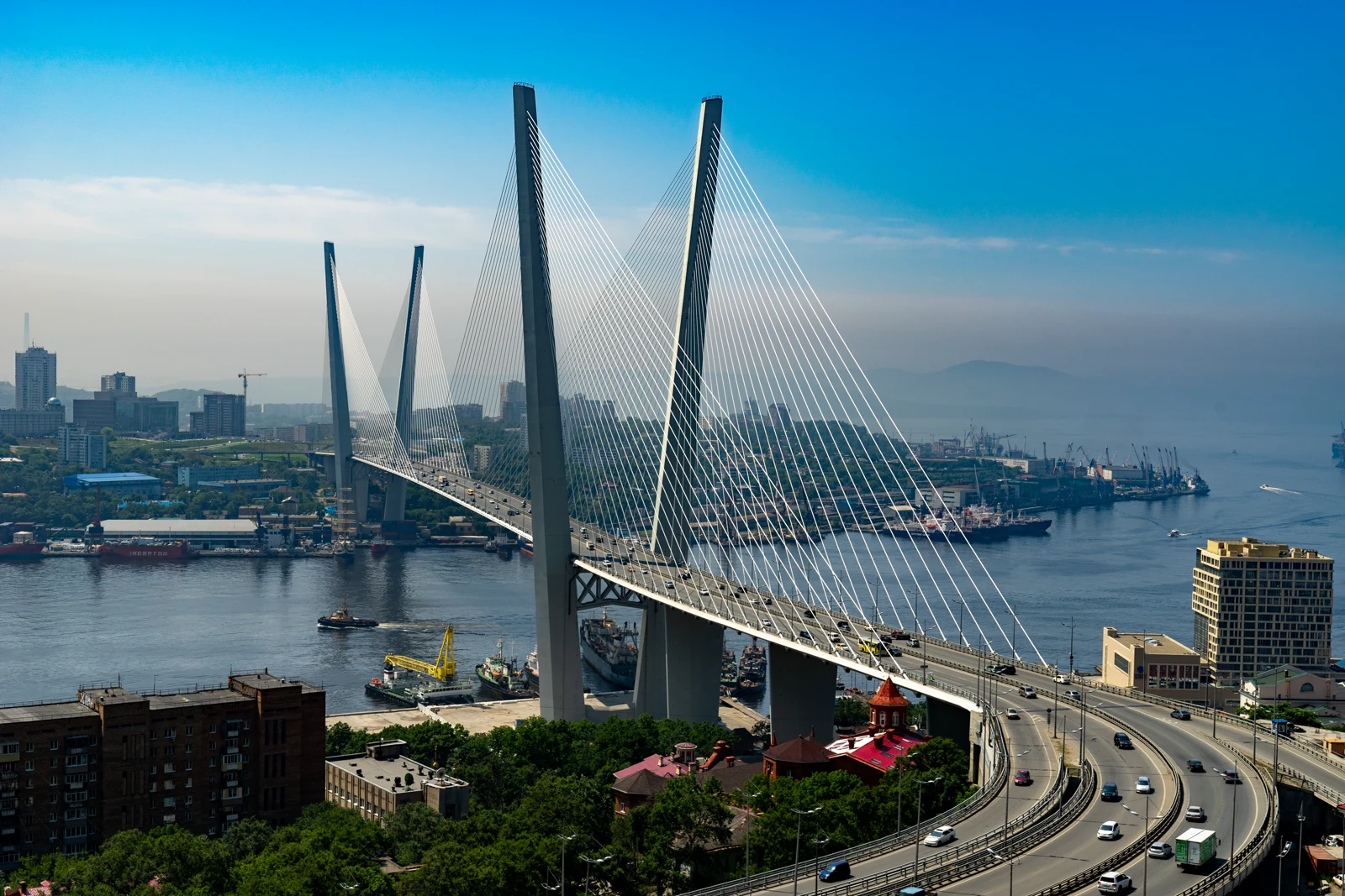 Golden Bridge crossing Golden Horn Bay in Vladivostok under a bright blue sky.